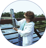USGS scientist inspecting a probe used for continual measurement of pH, dissolved oxygen, turbidity, and specific conductance. [Photo by Robert J. Shedlock, U.S. Geological Survey] (Click to view larger image.)