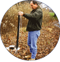 USGS scientist installing a passive-diffusion-bag sampler made of dialysis membrane in a monitoring well at Dover Air Force Base, Delaware. [Photo by Jeffrey R. Barbaro, U.S. Geological Survey] (Click to view larger image.)